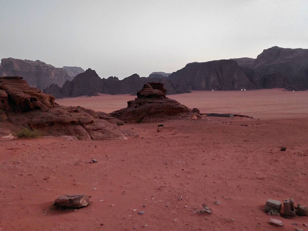 V diaľke pod skalami vidno svetlá iných kempov v púšti