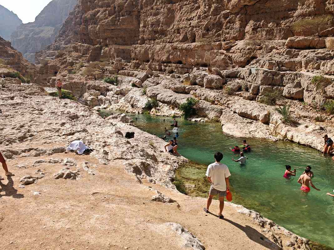 Wadi Shab, plno ľudí je vo vode, ale aj okolo na skalách